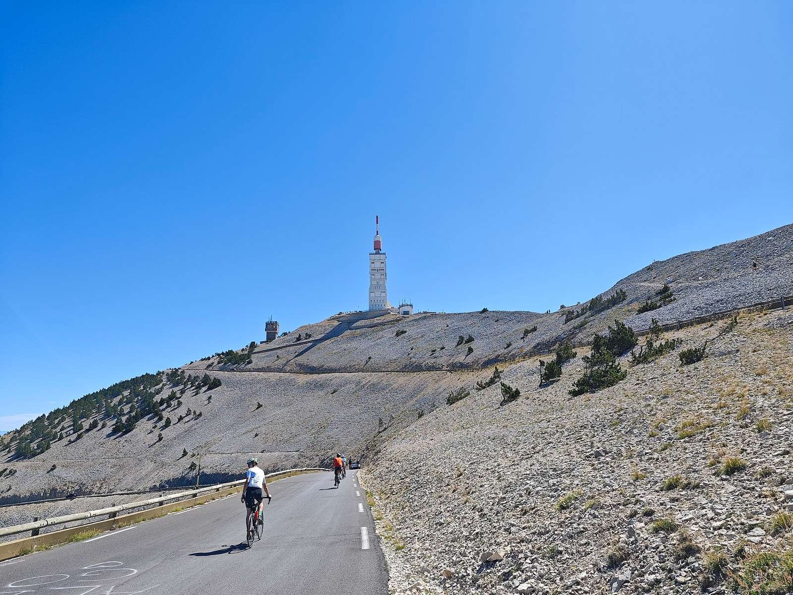 Des cyclistes sur la route du sommet du Mont Ventoux, entre les pierriers, sous l'antenne du sommet